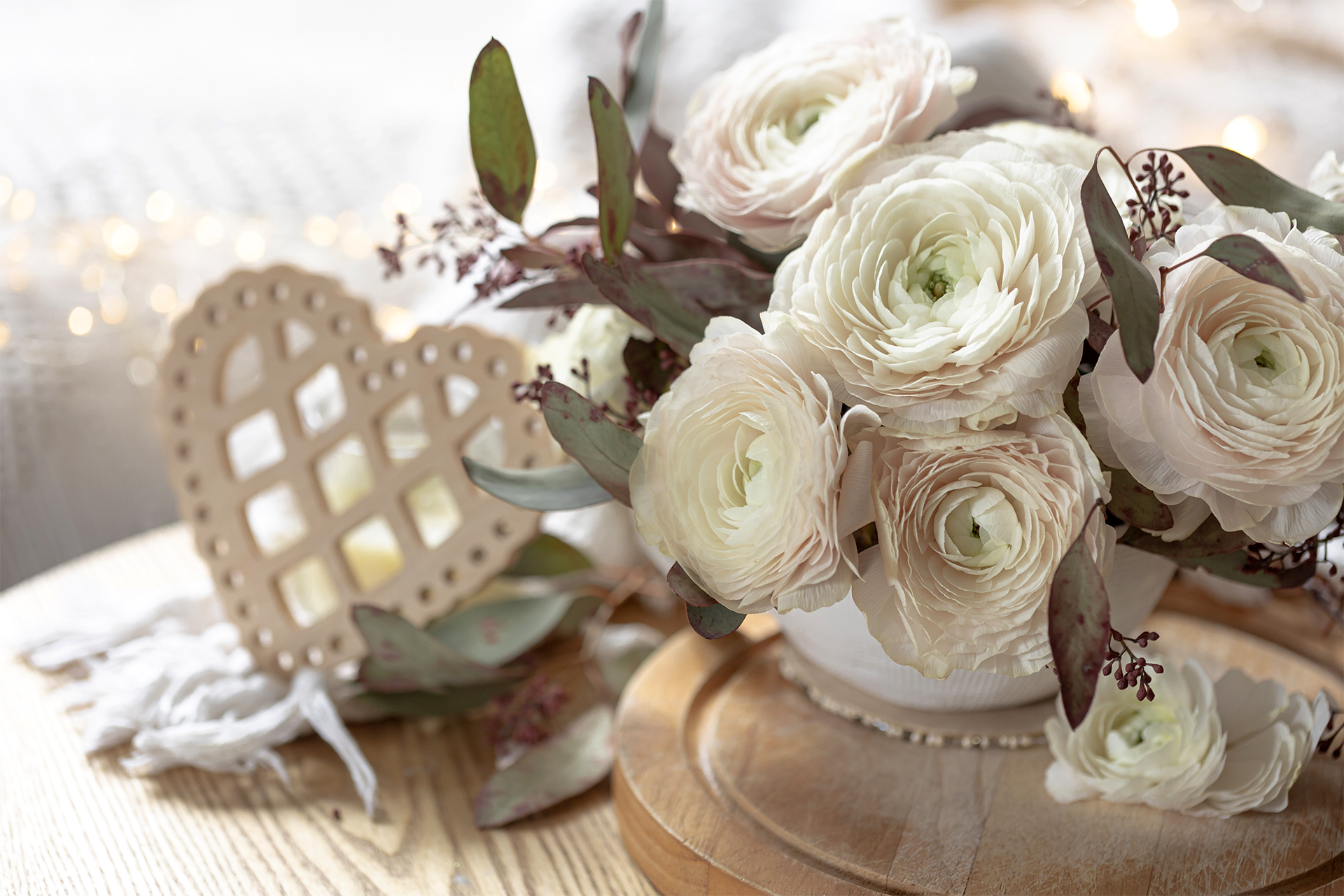 Spring composition with a bouquet of white buttercups and a decorative heart. Copy space.